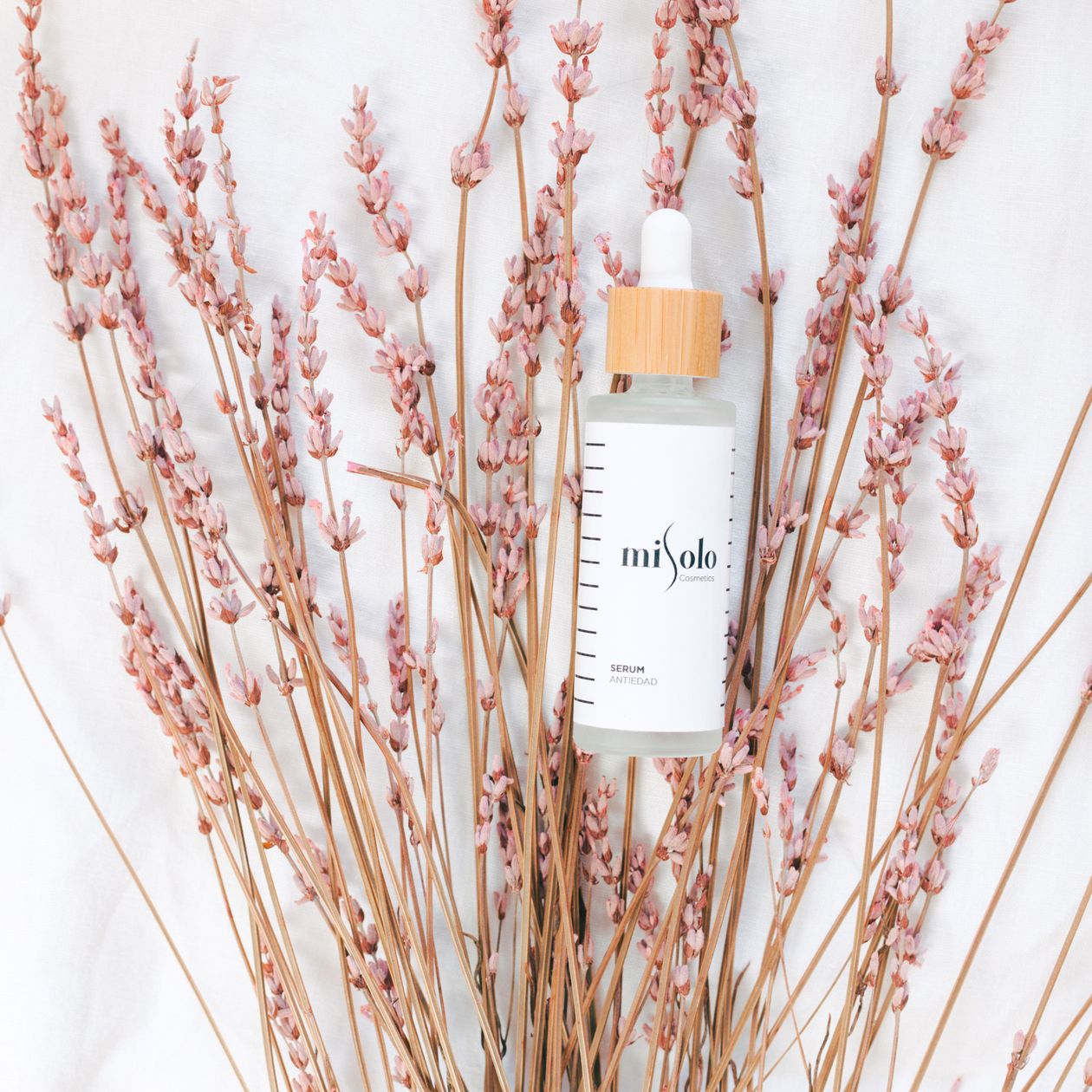 LumaLift serum bottle with dropper styled with pink flowers